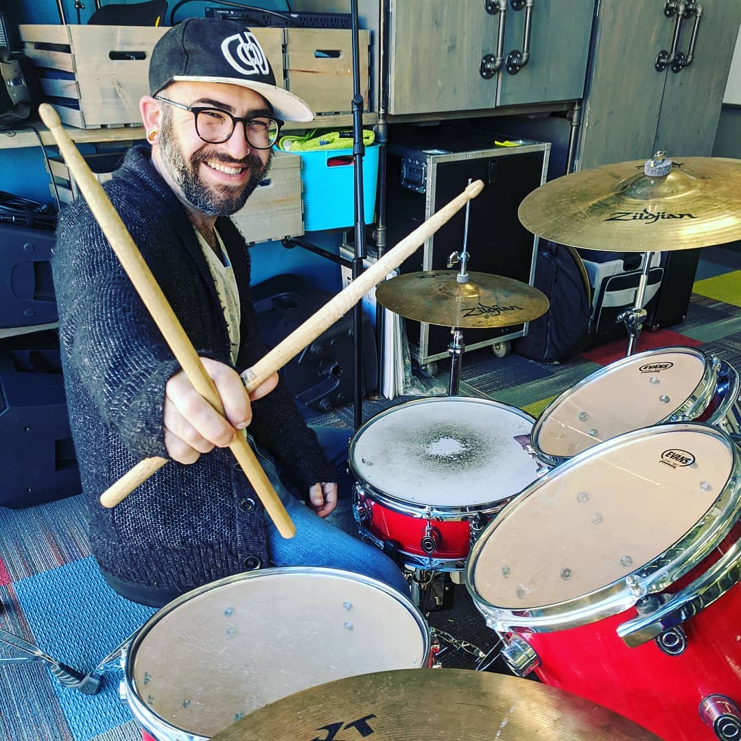 A man with beard and hat playing drums