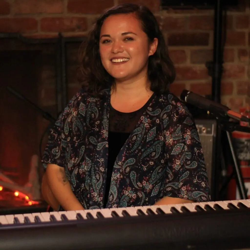 A woman sitting at the piano smiling for the camera.