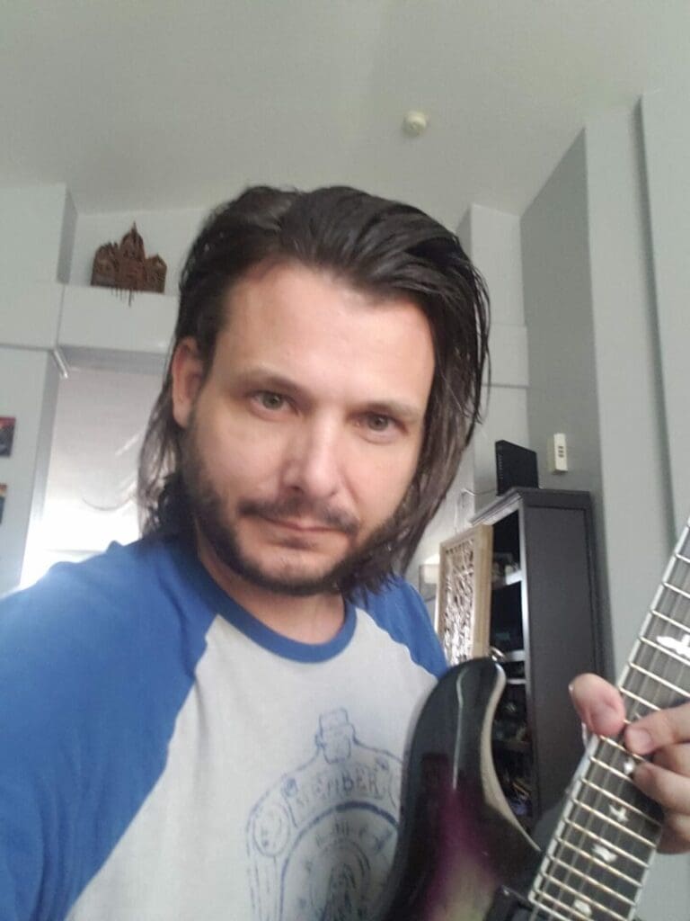 A man with long hair holding a guitar.