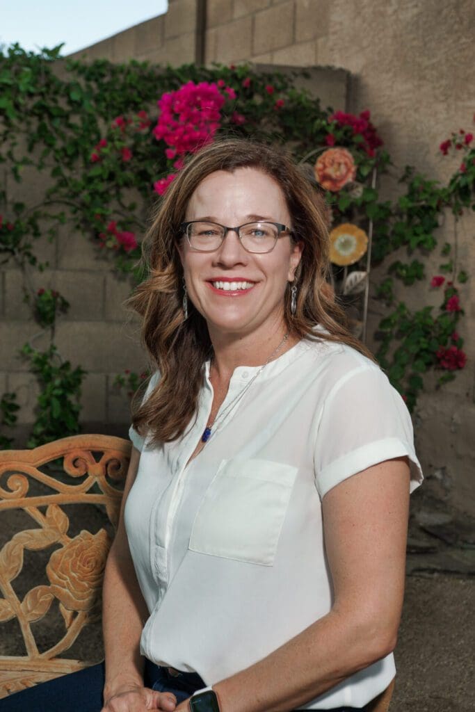 A woman standing in front of some flowers.