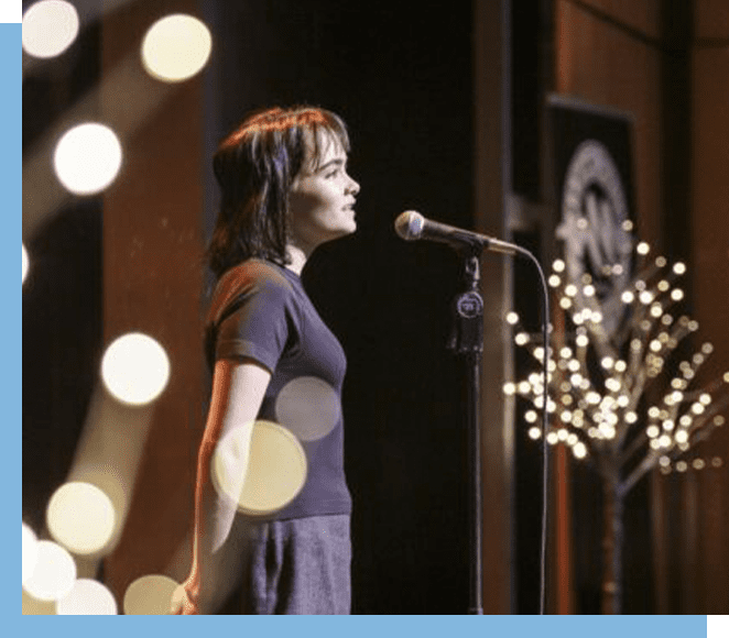 A woman standing on stage with a microphone.