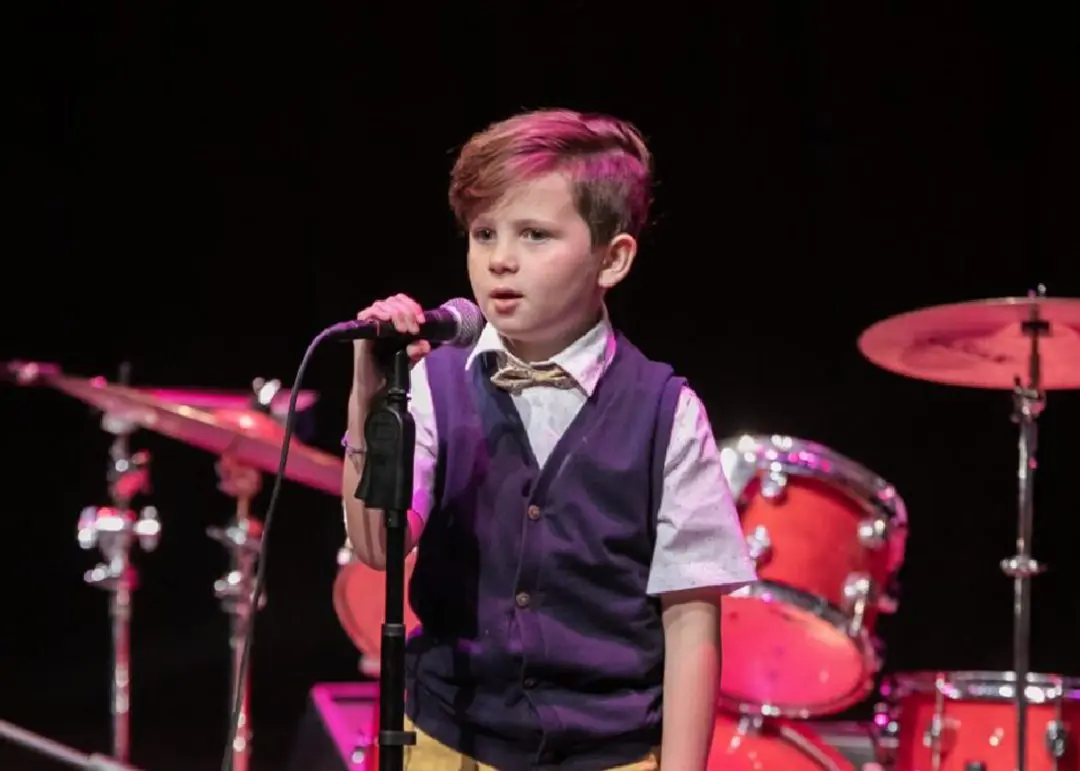 A young boy singing into a microphone.