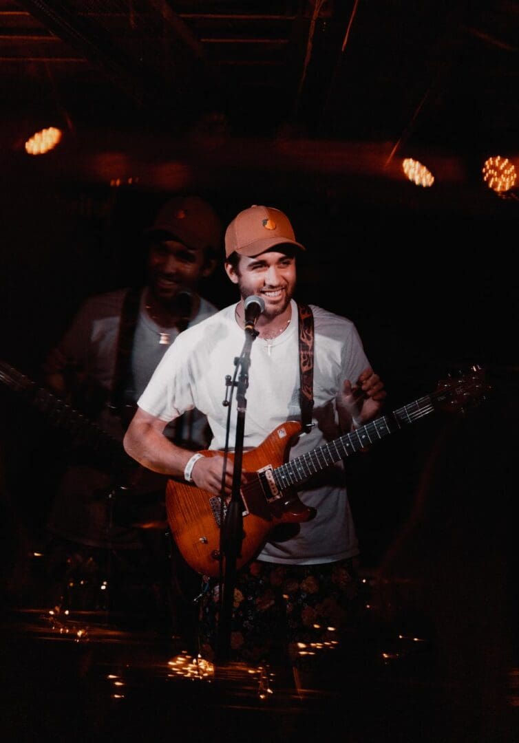 A man playing guitar and singing in front of an audience.