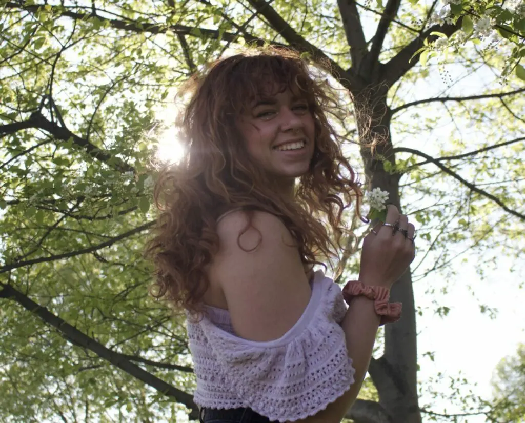 A woman hanging from a tree branch in the sun.