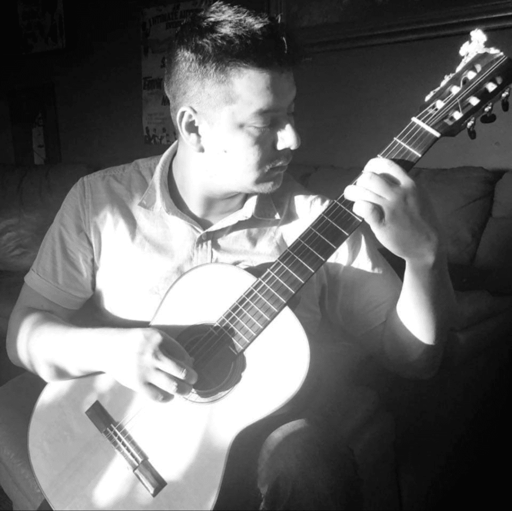 A man sitting on top of a couch holding a guitar.