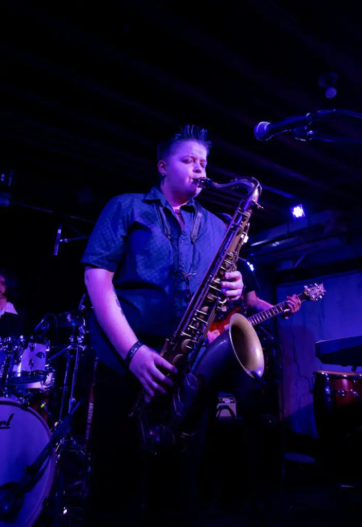 A man playing the saxophone in front of other musicians.