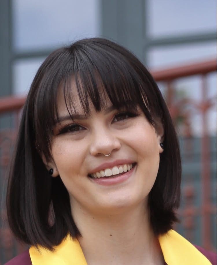 A woman with bangs smiles for the camera.