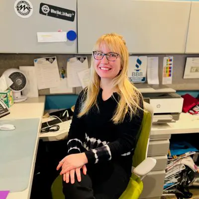 A woman sitting in front of a desk with many items on it.