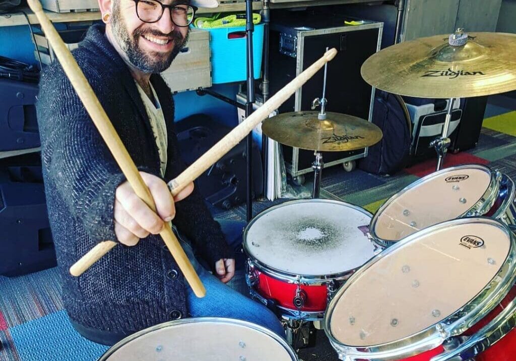 A man with beard and hat playing drums