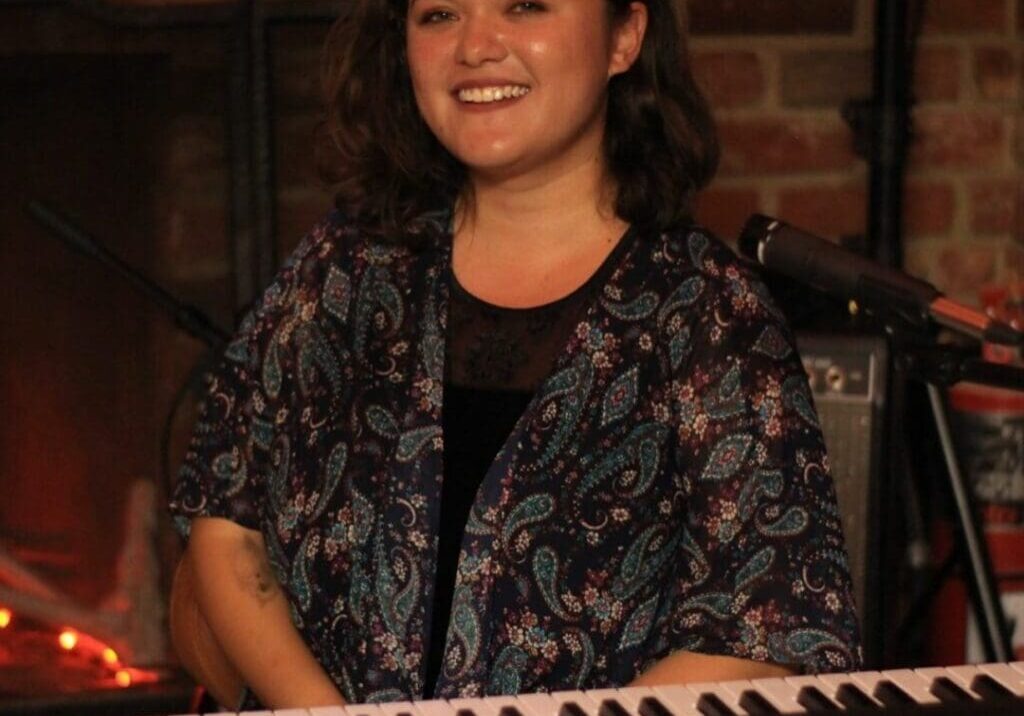 A woman sitting at the piano smiling for the camera.