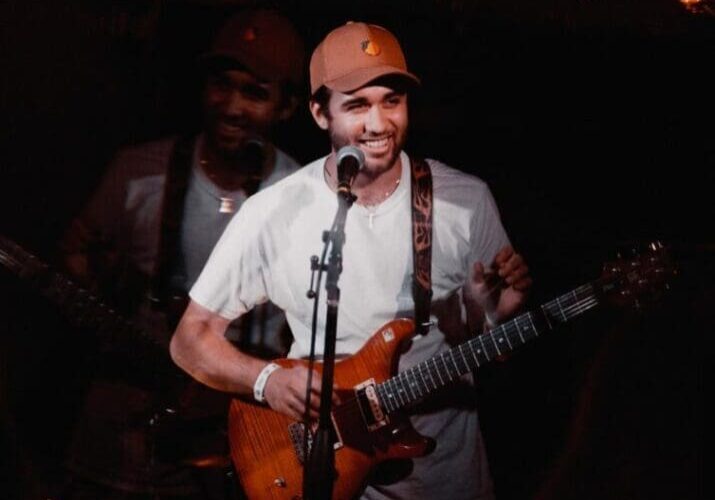 A man playing guitar and singing in front of an audience.