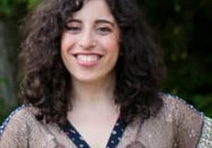 A woman with curly hair smiling for the camera.