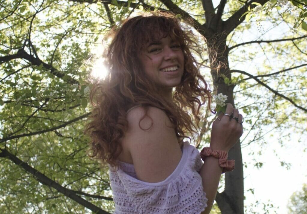 A woman hanging from a tree branch in the sun.