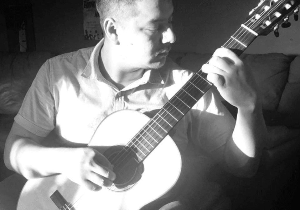 A man sitting on top of a couch holding a guitar.