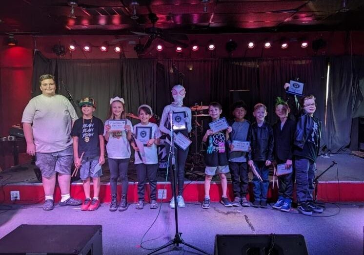 A group of young people standing on stage with microphones.