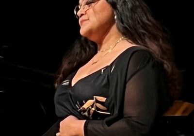 A woman in black dress holding a white object.